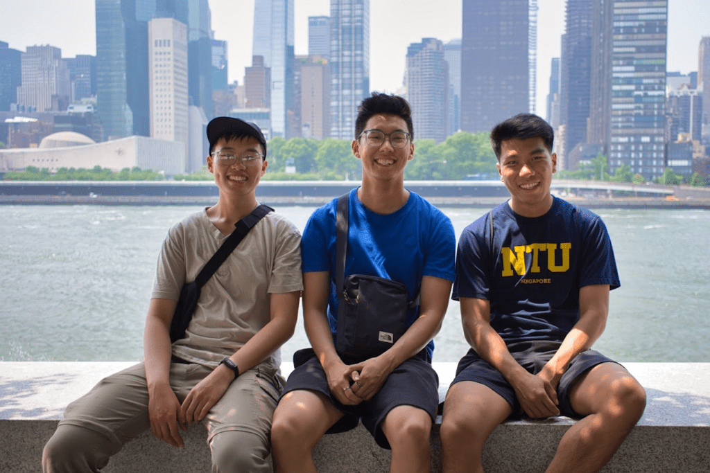 Code Monkeys sitting on a bench. Background is a body of water and tall buildings.