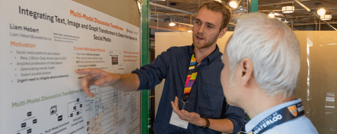 PhD student Liam Hebert presenting his research poster to a computer science professor