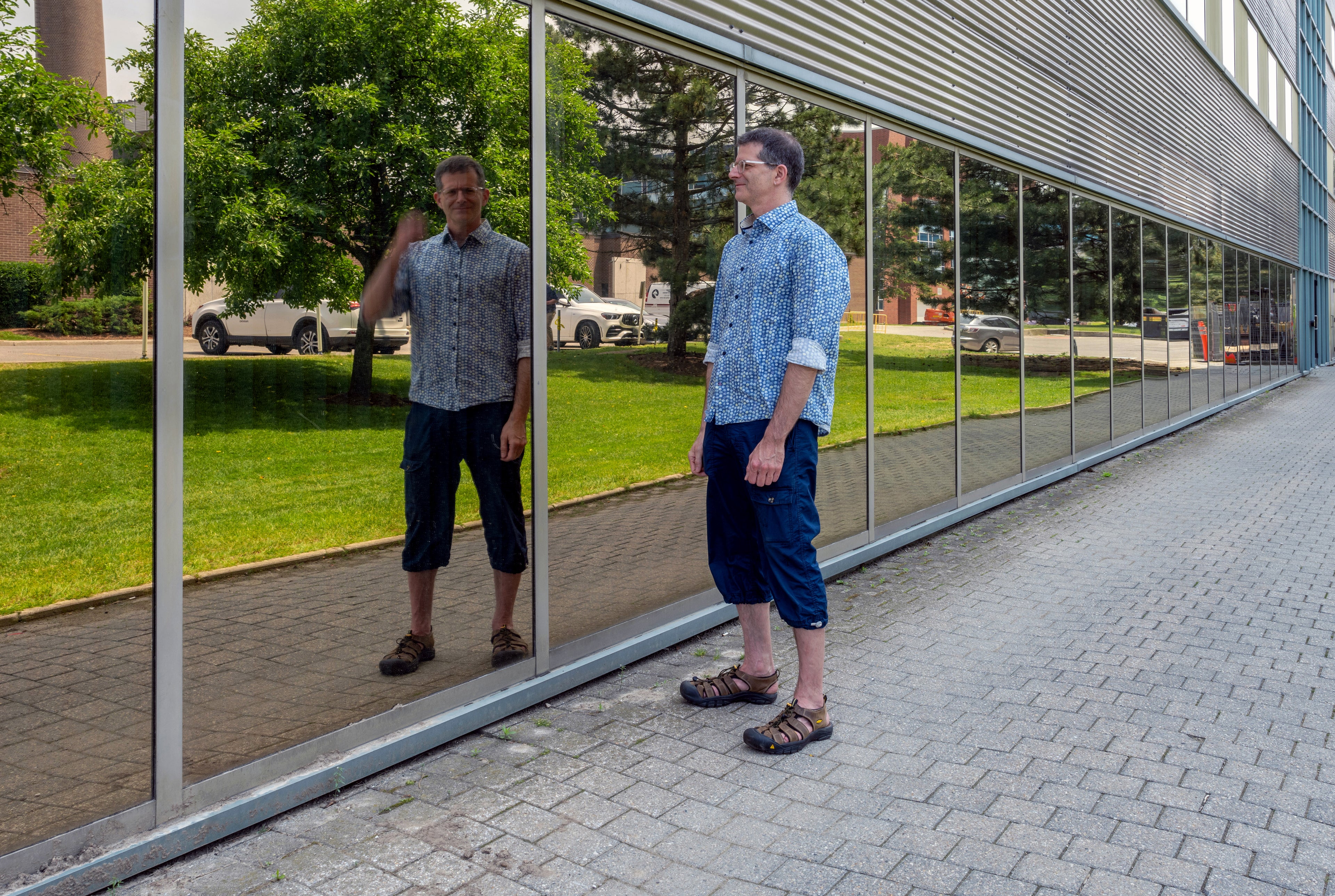 Professor Craig Kaplan outside the Davis Centre looking at his reflection